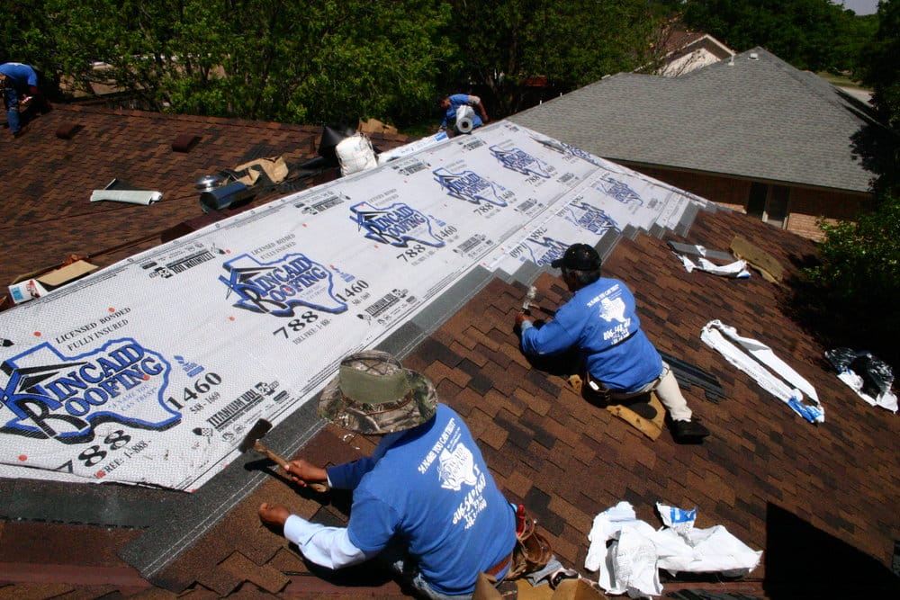 Crew rolling out Kincaid-branded underlayment on a roof deck