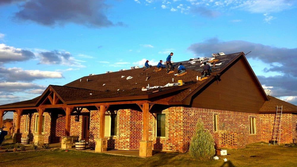 Kincaid crew on the roof of a brick home at sunset
